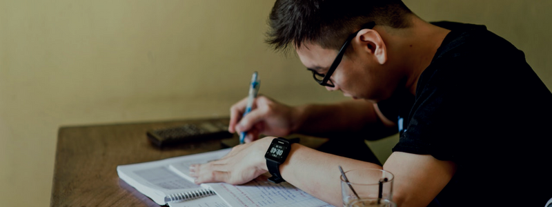 Focused student studying from a textbook and taking notes, indicative of a diligent learner in a Spanish class in Medellín, Colombia, enhancing their Colombia Spanish skills.