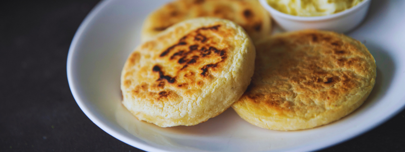 Freshly grilled arepas, a staple of Medellin's local cuisine, served with cheese on the side, perfect for those on a Medellin Food Tour looking to indulge in authentic Colombian flavors while learning Spanish in the heart of Colombia.