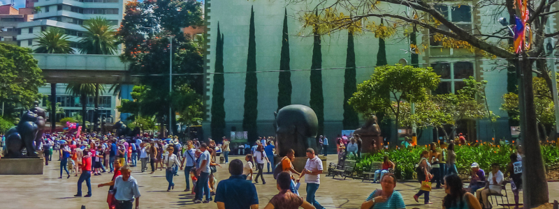Vibrant daily life at Plaza Botero in Medellín, a bustling public space featuring the iconic sculptures of Fernando Botero, ideal for inclusion in a Medellin Travel Guide and for those interested in Colombia Spanish culture, looking to learn Spanish, and immerse themselves in the local atmosphere of Medellín, Colombia.