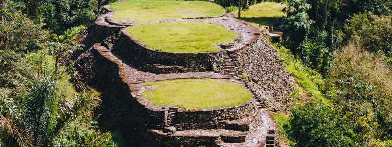 Ancient circular stone terraces of Ciudad Perdida amidst lush greenery, a testament to Colombia's rich history and a must-visit for those on a tour, enhancing their Spanish language skills in Medellín with Colombia Spanish.